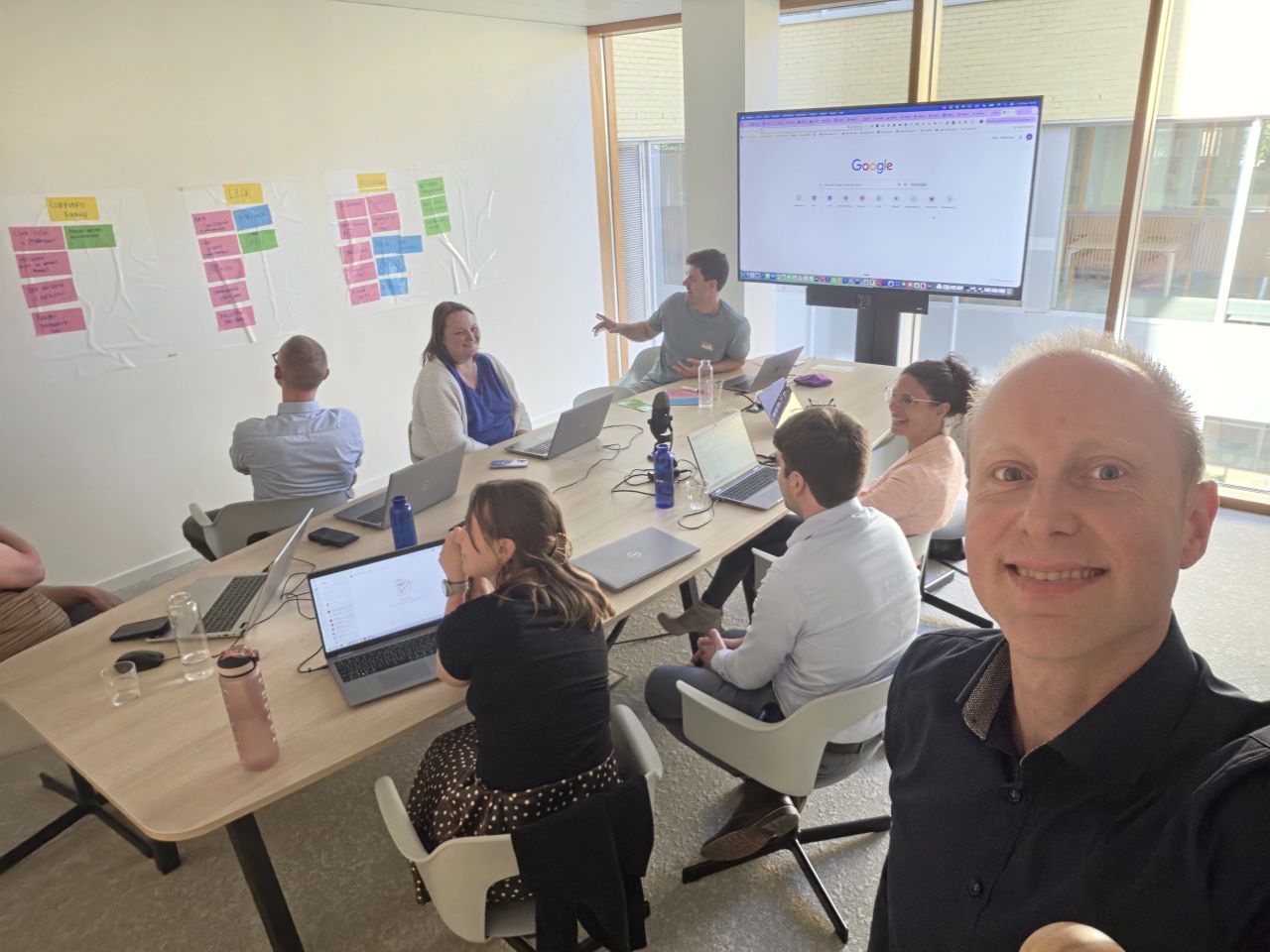 Werksessie met laptops en post-its aan de wand tijdens een A.I.-training.